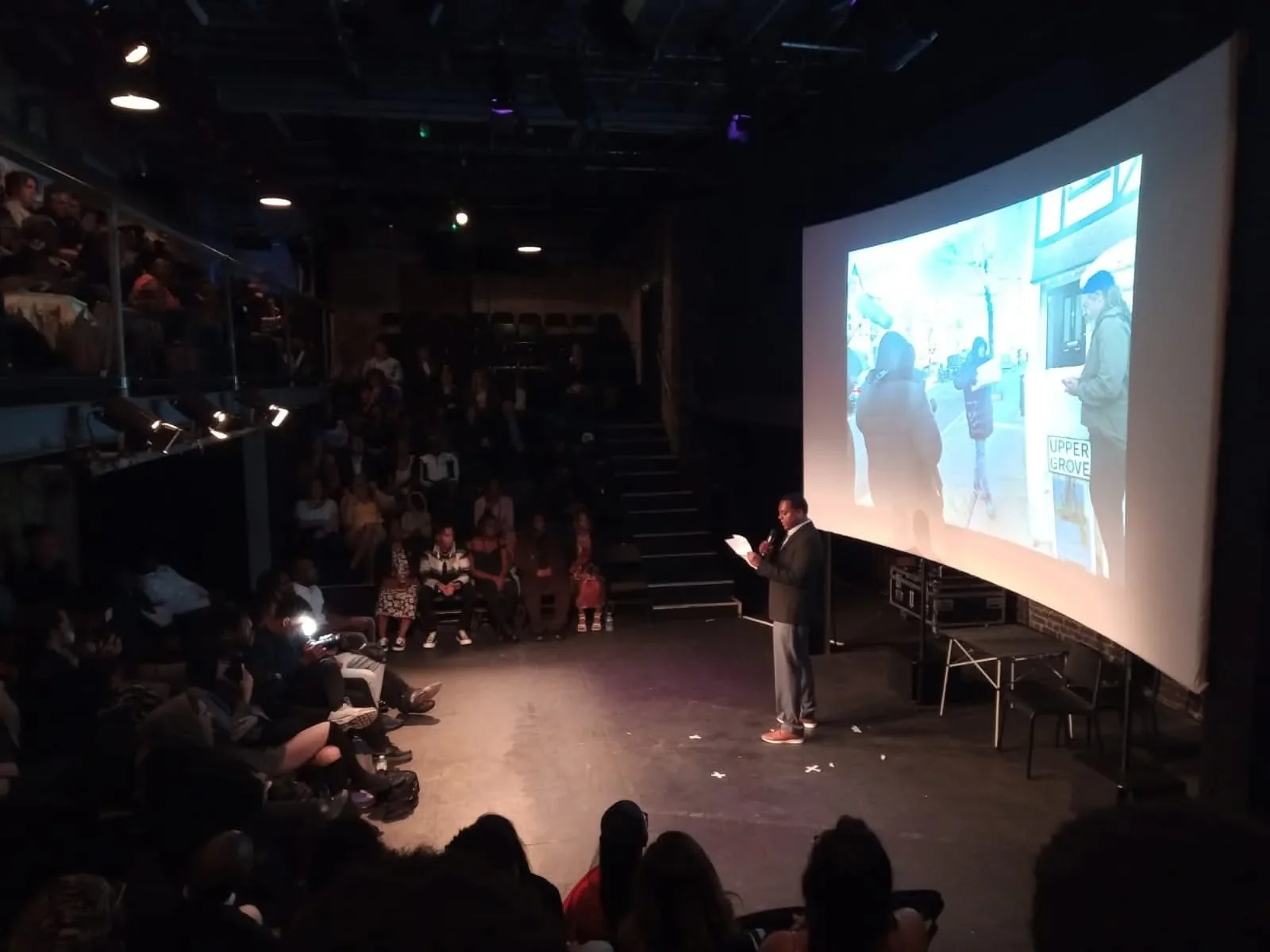 Picture of a man giving a talk in front of a projection in auditorium. Picture of a man giving a talk in front of a projection in auditorium.